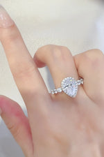 Hand wearing a pear-shaped diamond ring with side stones, elegant jewelry from Shopimist