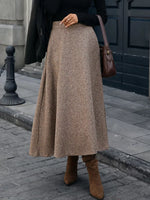 Woman wearing brown wool midi skirt, black top, brown boots and bag, stylish fall streetwear