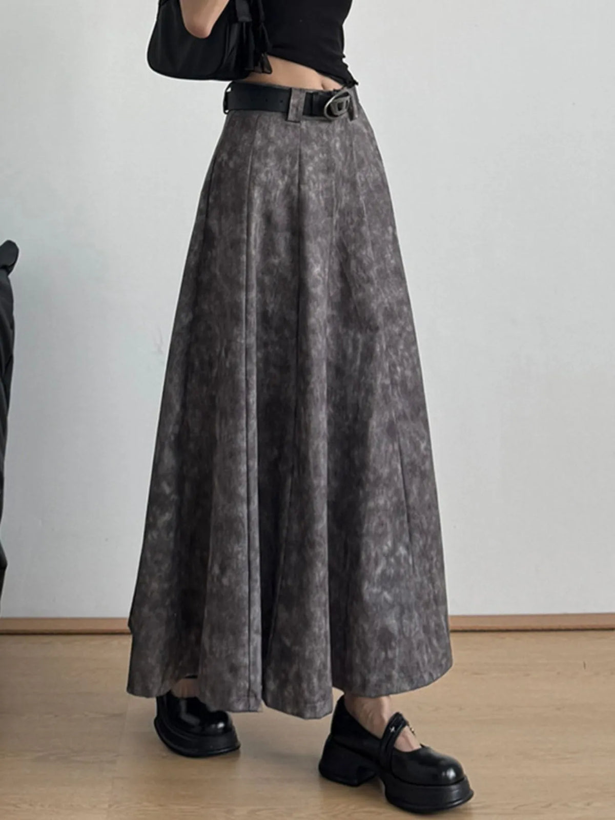 Woman wearing black crop top, high-waisted gray maxi skirt, black belt, and chunky loafers
