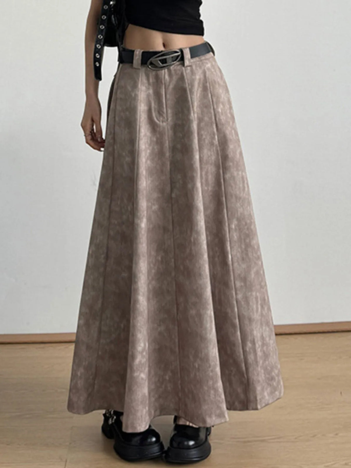 Woman wearing taupe pleated maxi skirt with black belt and chunky shoes, stylish fashion