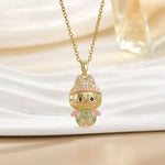 Gold cartoon character pendant necklace with pink and green accents on a light background