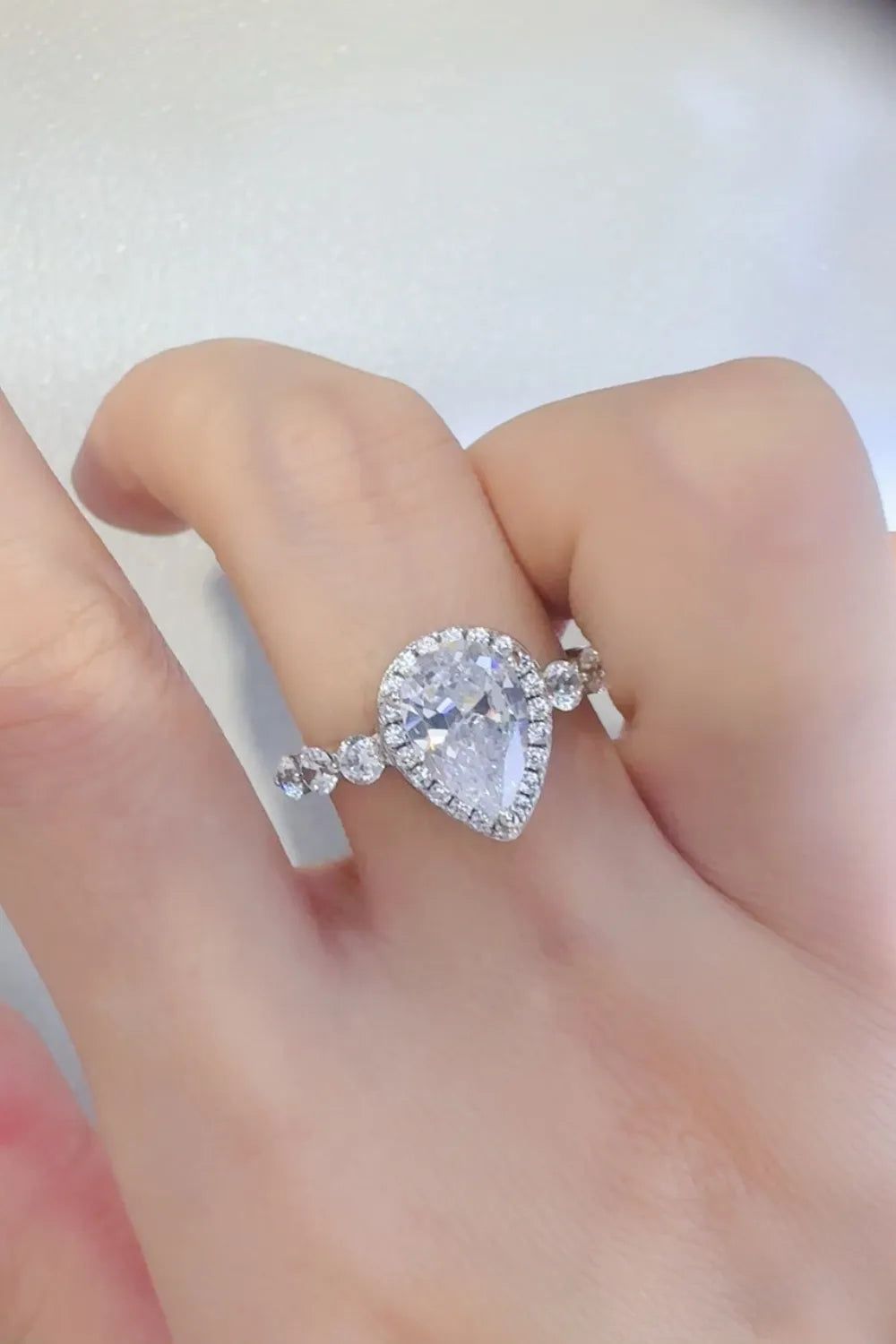 Pear-shaped diamond ring with halo and side stones on a hand, Shopimist jewelry fashion