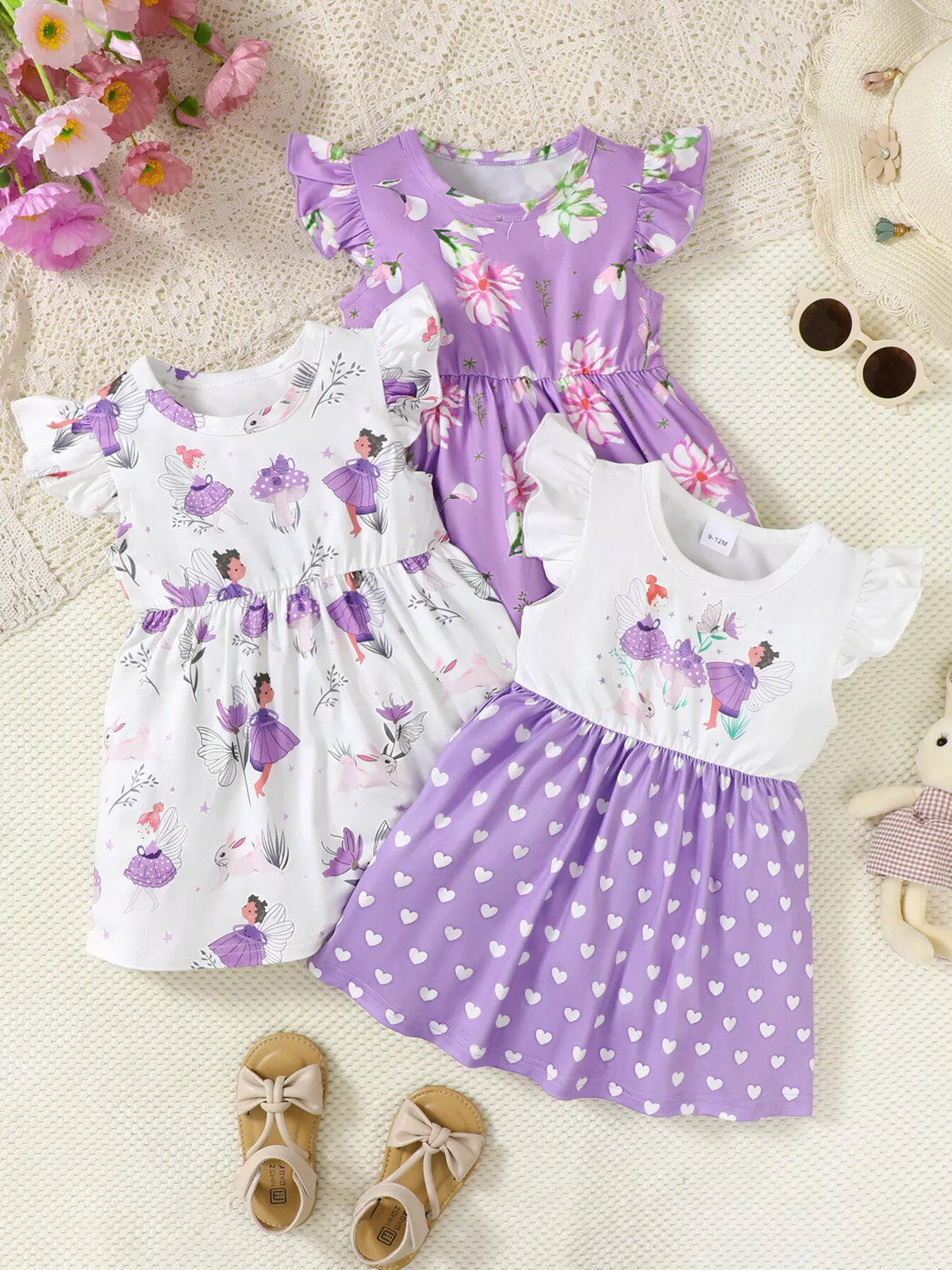 Three cute girls’ dresses with floral and fairy prints in purple and white, ideal for stylish kids fashion.