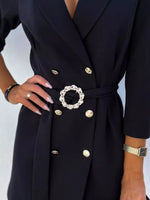 Woman wearing a stylish black double-breasted blazer dress with gold buttons and a jeweled belt.