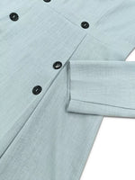 Light blue buttoned shirt with black buttons, close-up on fabric and sleeve from Shopimist fashion.