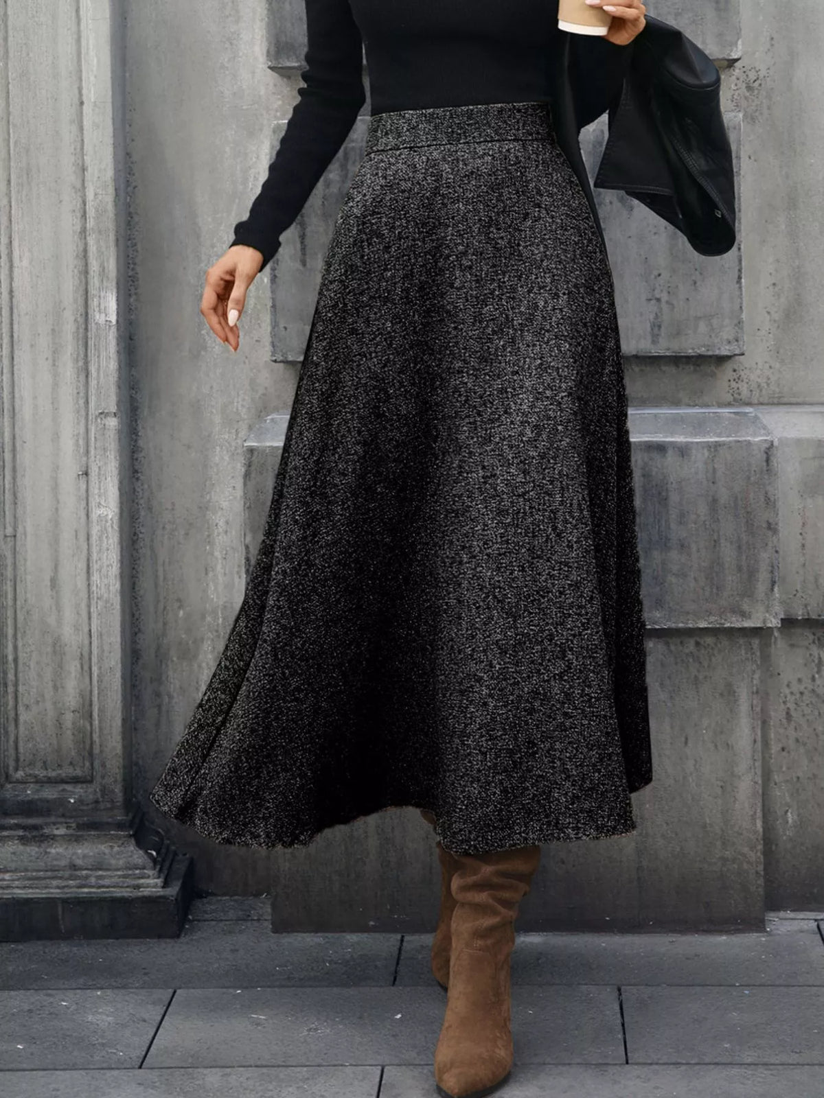 Woman in black knit sweater and gray midi skirt, brown suede boots, city street style
