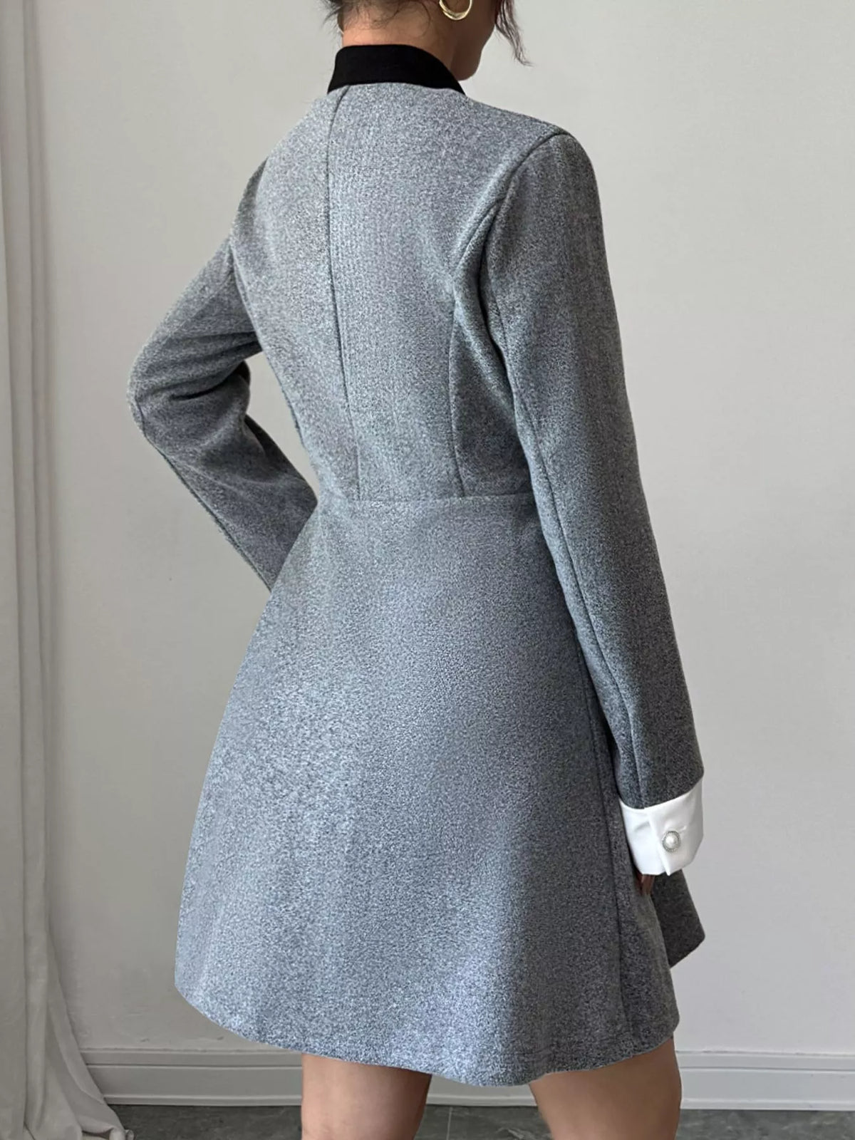 Woman in a gray textured blazer dress with black collar and white cuffs, stylish fashion