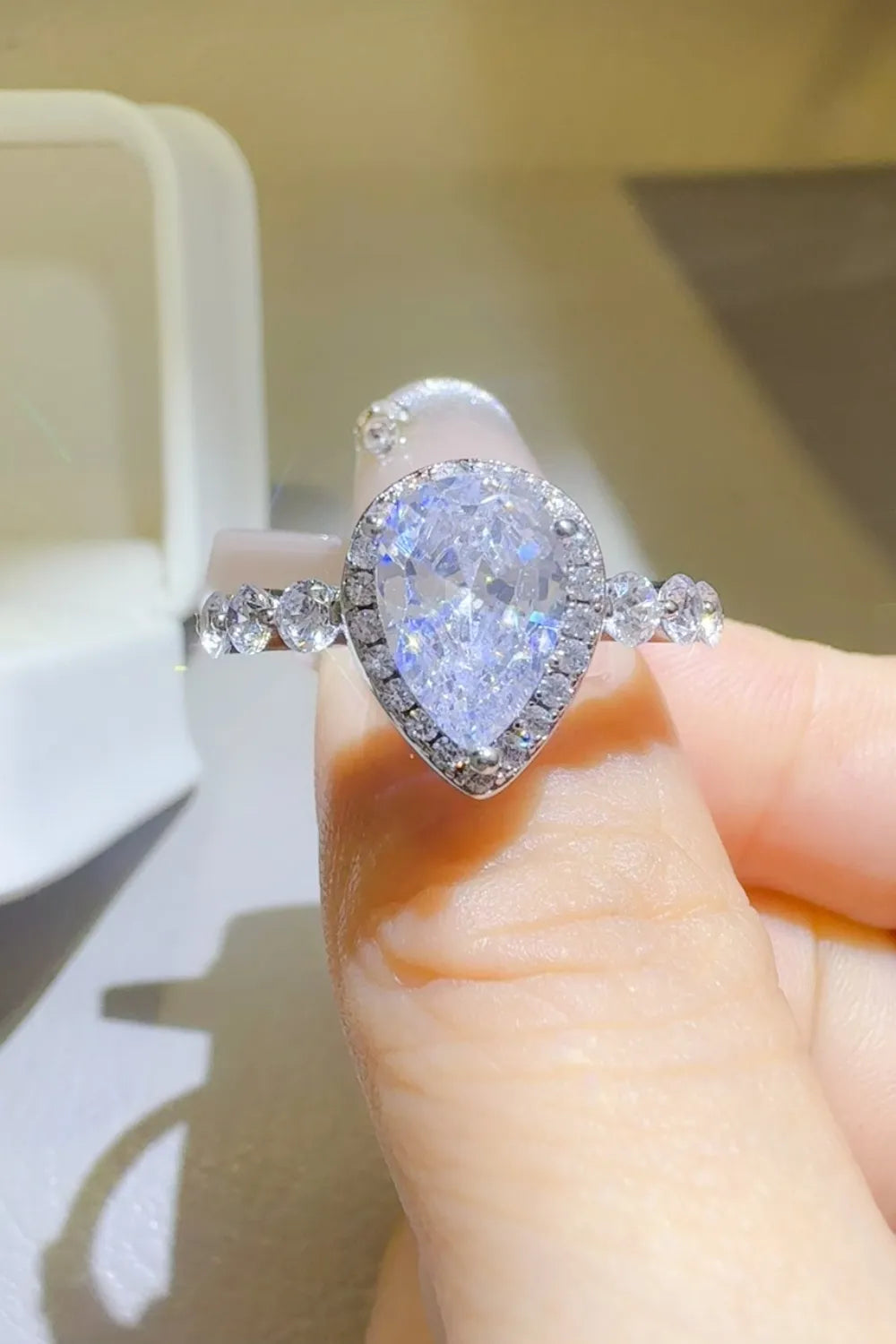 Pear-shaped diamond ring with side stones on hand, elegant fine jewelry from Shopimist