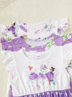 Stack of purple and white baby girl dresses with fairy and floral prints on a textured surface