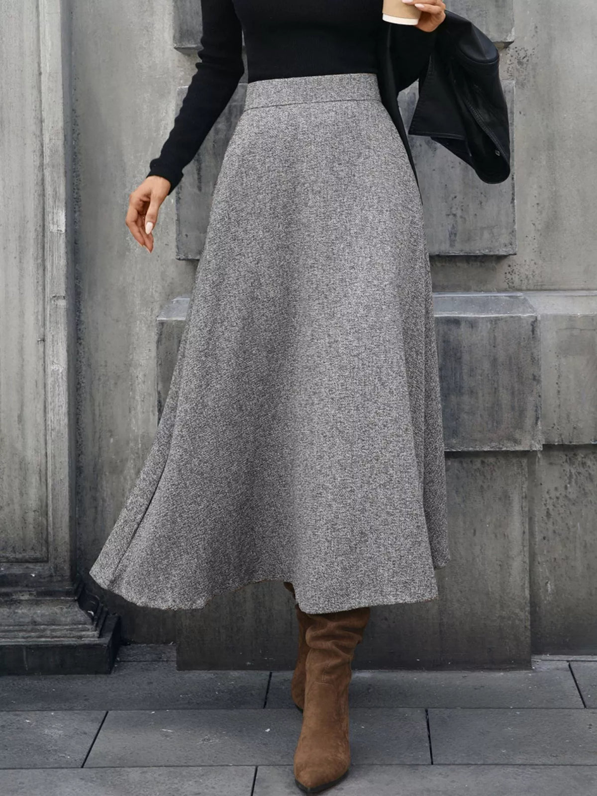 Woman in grey wool midi skirt, black top, and brown boots, holding coffee outside, Shopimist fashion