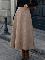 Woman wearing a brown wool midi skirt, black top, and boots on a city street