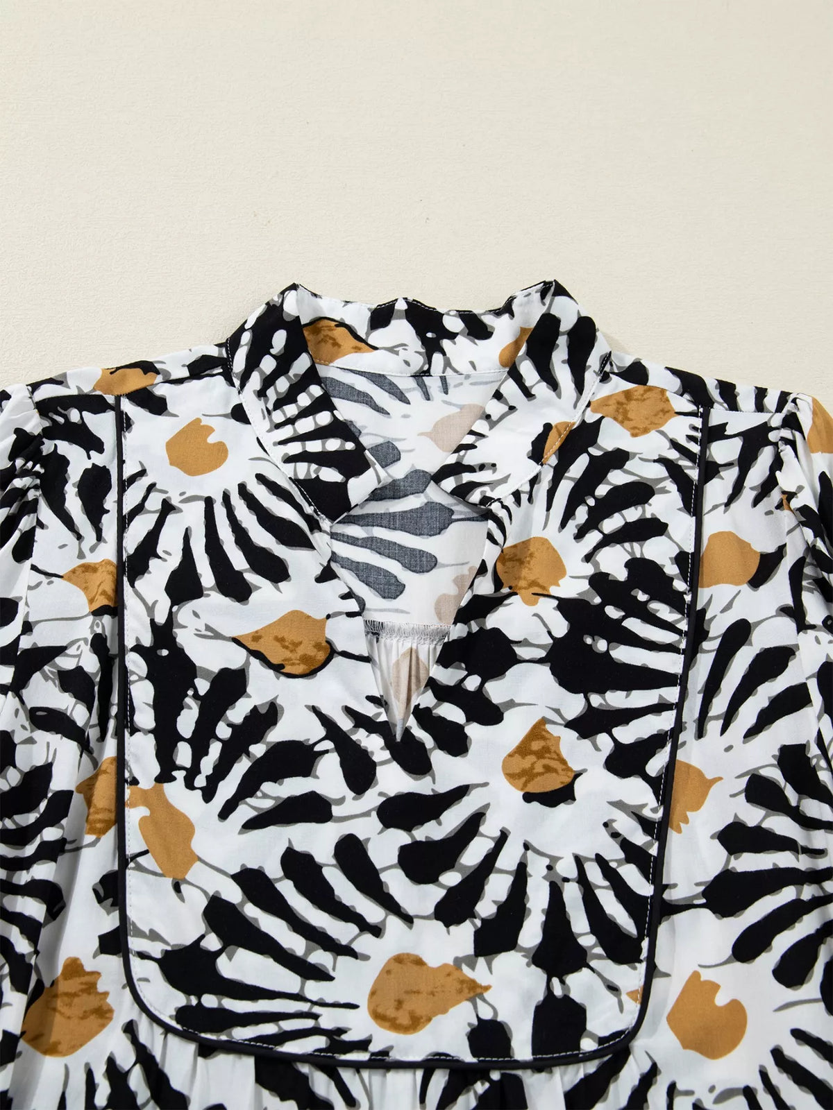 White blouse with black and brown abstract leaf print, v-neck, modern fashion detail