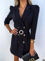 Woman in a black blazer dress with gold buttons and a belt, holding a black clutch