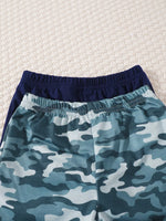 Closeup of kids’ blue camo and navy elastic waist jogger pants on textured white surface