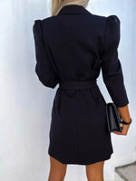Woman wearing a tailored black blazer dress holding a black clutch, fashion apparel