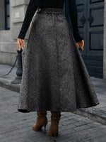 Woman wearing a gray A-line maxi skirt and brown heeled boots, street style fashion